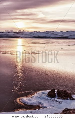 Ice floes floating on the fog water in the lake Baikal and hill, Russia. Sunset