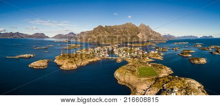 Aerial view of Henningsvaer, its scenic football field and mountains in the background. Henningsvaer is a fishing village located on several small islands in the Lofoten archipelago in Norway.