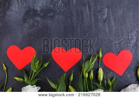 Tip of Japanese roses with carved red hearts on a stone background
