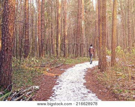 The girl runs along the snow trail in the autumn forest. Image on the topic of maintaining the body in good physical shape, strengthening health and immunity, a healthy lifestyle