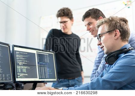 Startup business and entrepreneurship. Young software developers team brainstorming and programming on desktop computer in startup company share office space.
