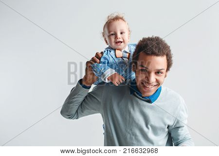 A happy family of afro man and caucasian child on white studio background