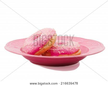 Two donuts with a pink icing with slices of white chocolate in a plate on a white isolated background
