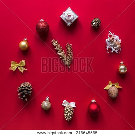 on a red background a layout of Christmas ornaments gift bows of nuts and cones in the form of hours that are thrown 12 new year arrow Christmas tree branches concept