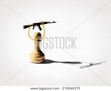 A pawn holds a gun above his head. The concept of political and religious manipulation of people.