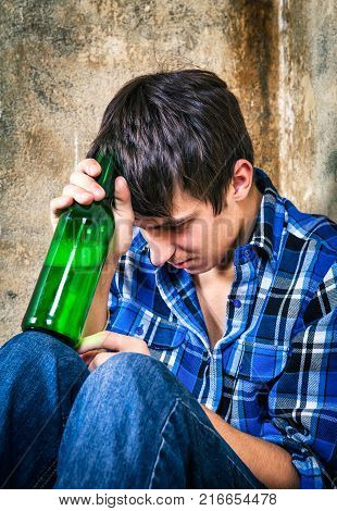 Sad Young Man with a Beer by the Old Wall