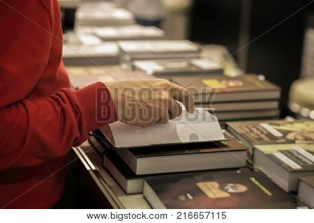 Close-up of hands of the elderly person with open book, bookstore, library. Real scene. Education concept, Self-study, reading fiction, pension, interests in the elderly, life style