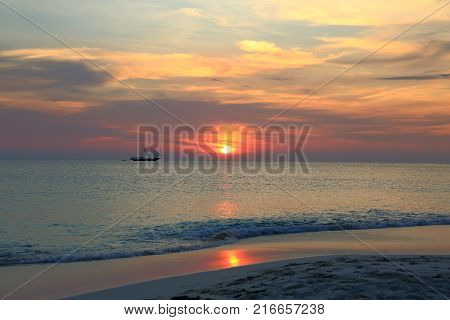 Gorgeous colorful sunset on Caribbean sea, Unforgettable view of Aruba landscape. Small boat on horizon line
