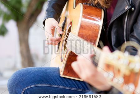 Closeup of acoustic guitar and woman hands on strings. Music and creative concept