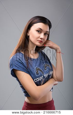 thoughtful girl in a blue t-shirt touching face hand on a gray background. Studio shoot
