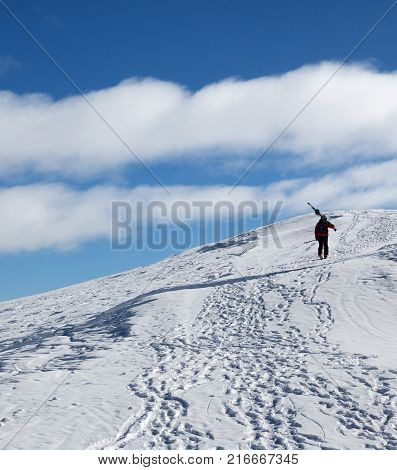 Skier with skis on his shoulder go up to top of snowy mountain in cold sun day. Caucasus Mountains in winter Georgia region Gudauri Mt. Kudebi.