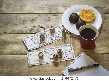 Cards And Chips For Playing Bingo On A Wooden Table. Cup With Coffee