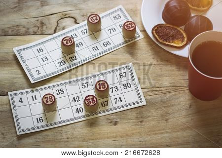 Cards And Chips For Playing Bingo On A Wooden Table. Cup With Coffee