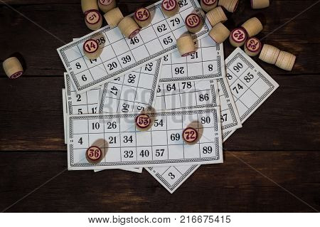 On A Wooden Bingo Table Game, A Cup With A Coffee, A Biscuit And An Orange Slice