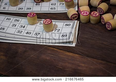 On A Wooden Bingo Table Game, A Cup With A Coffee, A Biscuit And An Orange Slice