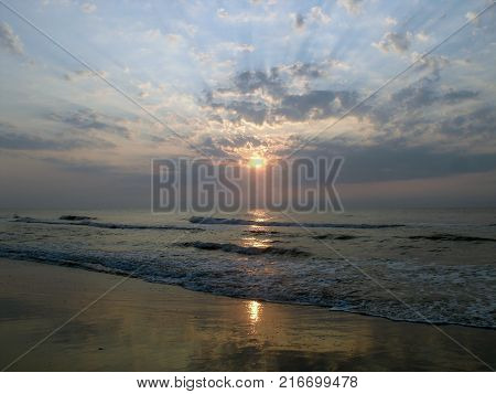 Sun peeking through clouds at sunset over ocean