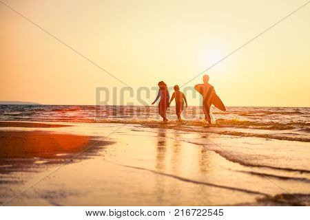 Silhouette of Young surfers with brethren they're relaxing on sunset beach. Summer activity of people on the beach concept. Extreme sports concept.