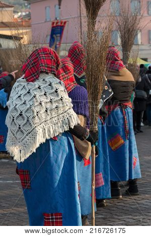 Group of Women with Red Scottish Kerchief Shawles and Brooms in Public Ground.