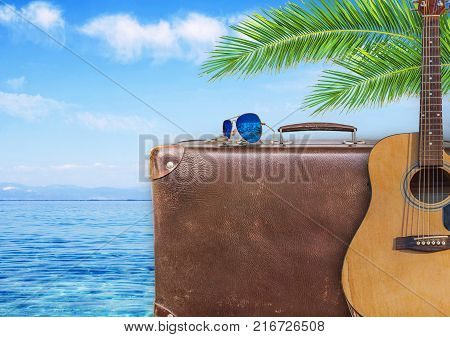 Concept of summer traveling with old suitcase and guitar