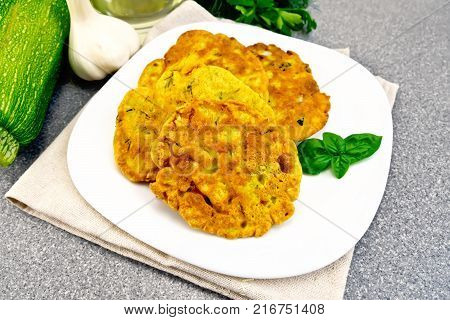 Indian chick-pea flour flatbreads with zucchini and fresh herbs, basil in a plate on a napkin, garlic and oil in the decanter on the background of the stone table