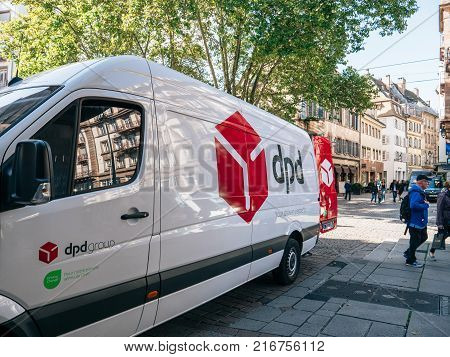 STRASBOURG FRANCE - OCTOBER 3 2017: Fast DPD postal courier distributing parcels near the white delivery van parked on a French street in central town