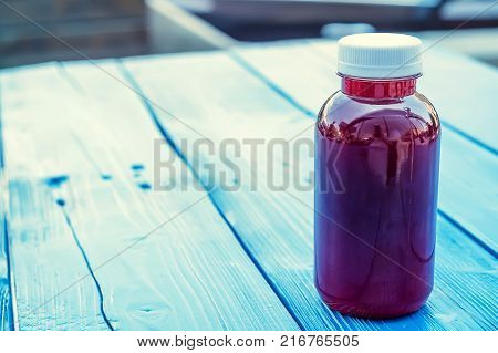 Close up soft fruit drink in plastic bottle on wooden table in outdoors restaurant