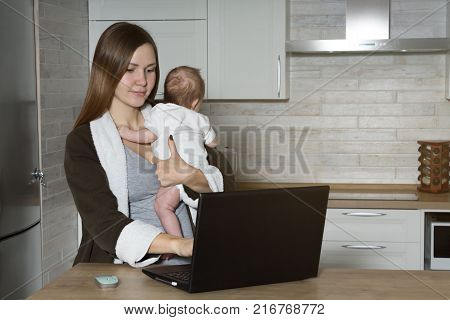 Woman with Baby Working at Computer at Home