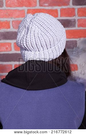 girl in hat and fur coat, against a brick wall background