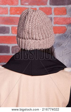 girl in hat and fur coat, against a brick wall background