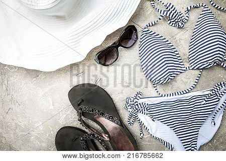 Female summer striped bikini swimsuit, clothes and accessories collection on gray background. Flat lay, top view