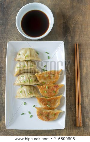 Eight boiled or fried jiaozi or gedza served with soy sauce. Selective focus.
