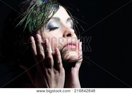 Portrait of a young girl with evening make-up and feather decora