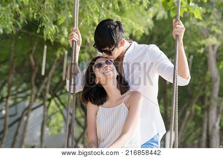 Happy asian couple kissing in the park on the beach. Man kissing on head woman. Travel and lover concept.