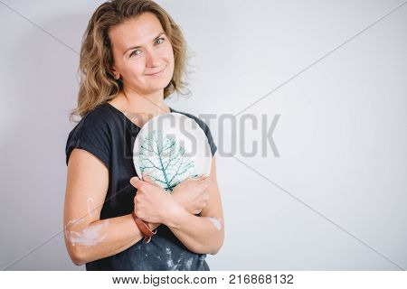 potter, tools, ceramics art concept - handsome young brunette female stand with finished utensils, smiling ceramist at workplace with baked cups and jugs at background