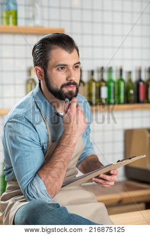 Creative owner. Clever calm handsome owner of a new beautiful cafe sitting comfortably while thinking about the necessary changes and looking into the distance