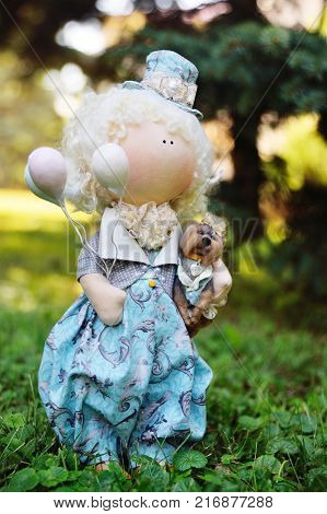 A handmade doll holds balloons and a small dog. Nostalgia, magic, kindness, childhood, dreams