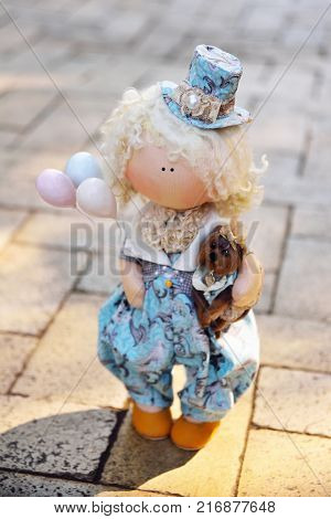 A handmade doll holds balloons and a small dog. Nostalgia, magic, kindness, childhood, dreams