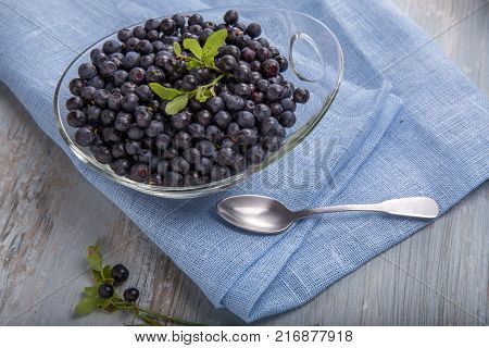 Fresh forest berry, blueberries in a glass plate on a wooden table.