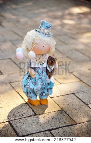 A handmade doll holds balloons and a small dog. Nostalgia, magic, kindness, childhood, dreams