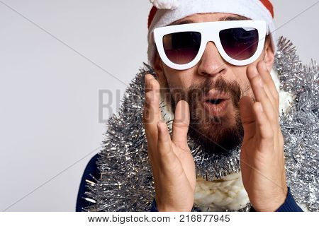 man with a beard in glasses holds hands near the face, portrait, emotions, holiday.