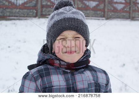 The boy in the winter dressed in a cap closed his eyes
