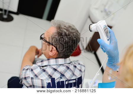 baldness. doctor examines an elderly man hair using special equipment - trihoskopa