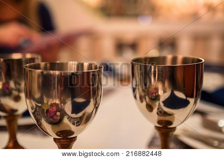Close up image of several metal wine glasses on table in restaurant with blurred background