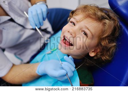 smiling child sitting in a blue chair dental