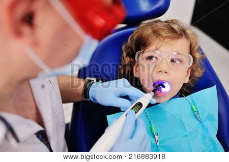 dentist in dental fillings to put glasses baby boy with curly hair