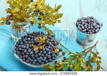 Fresh forest berry, blueberries in a glass plate on a wooden table.
