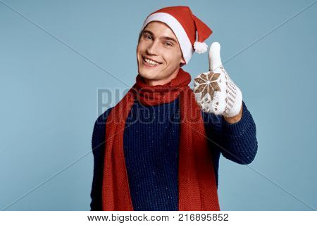 a man in mittens and a New Year hat shows a thumbs up, a light blue background, a free copy space, a new year.