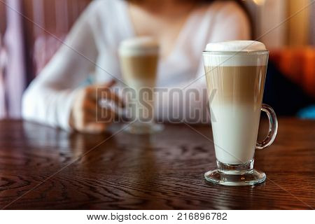 Latte macchiato in tall glass close up. Coffee on a table in cafe