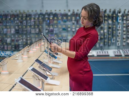 Smart female customer choosing digital tablet in the mobile phone shop. difficult decision. Various choice