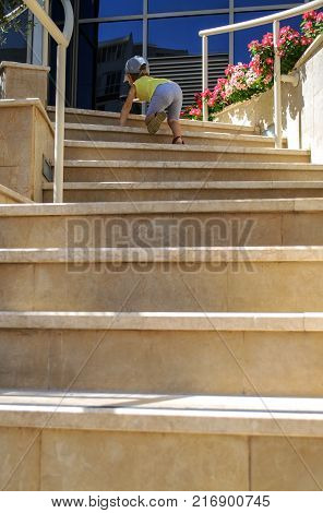 Small child climbs up on steps of beige stairs